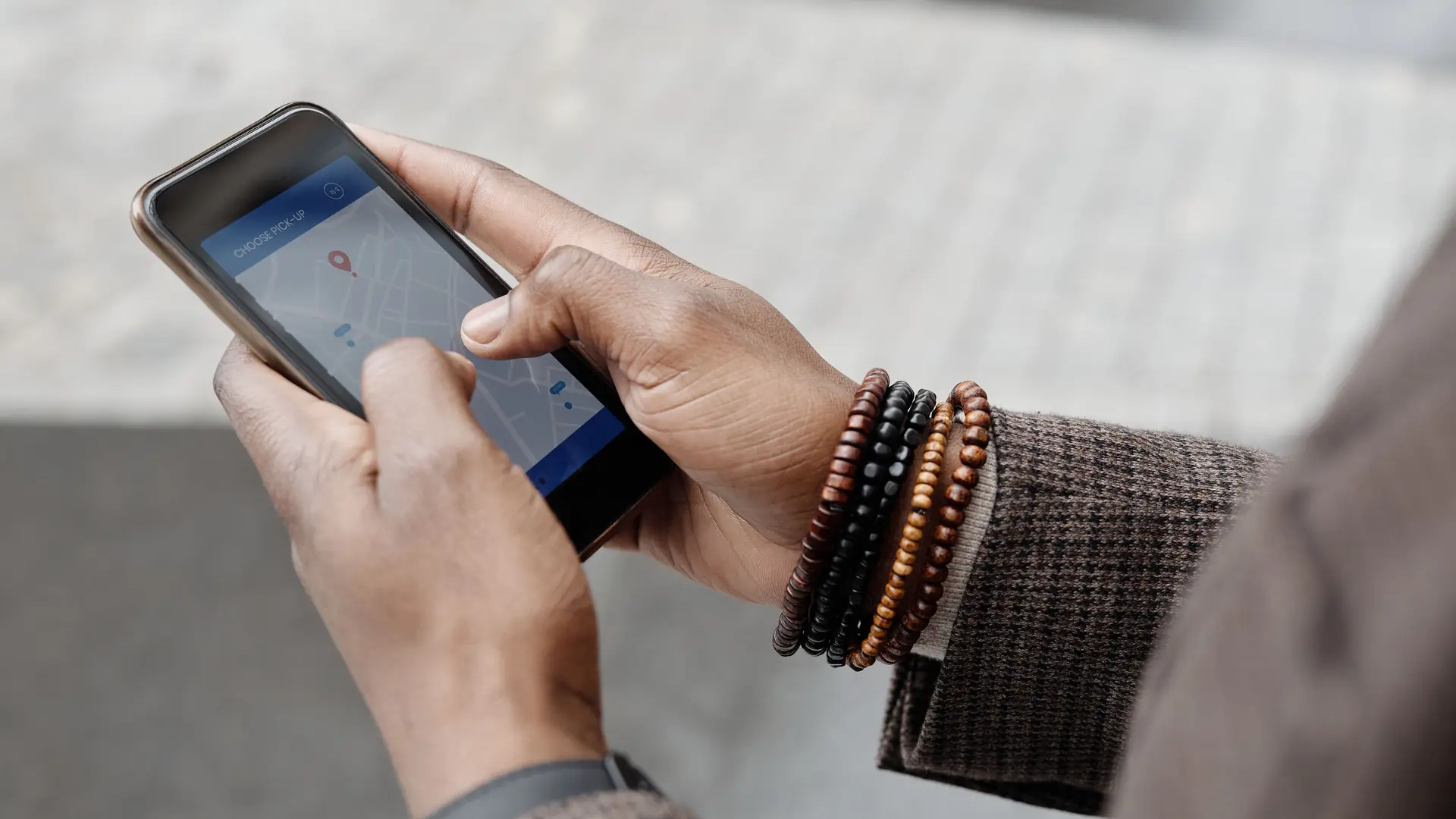 Hands holding a smartphone with a map app open outdoors