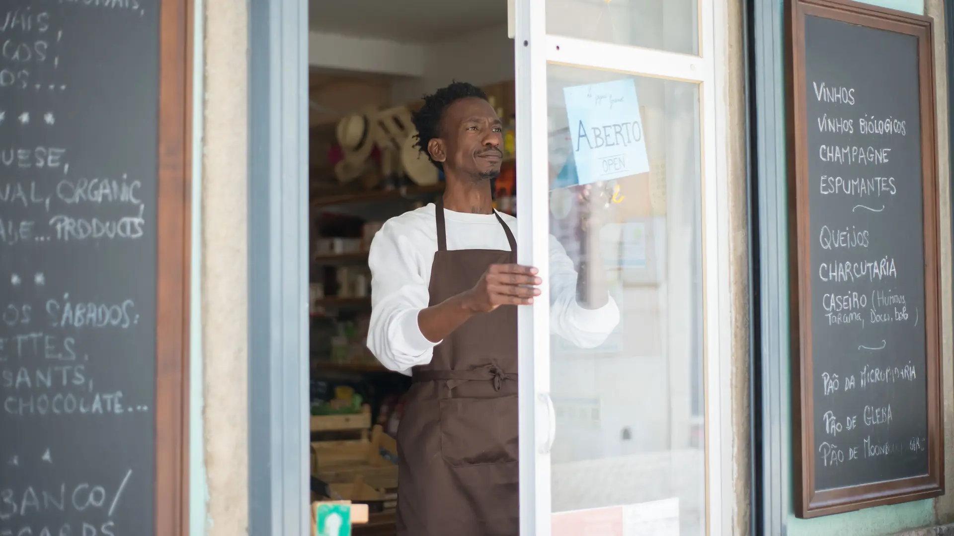 Shop owner in an apron opening the door of his store for the day