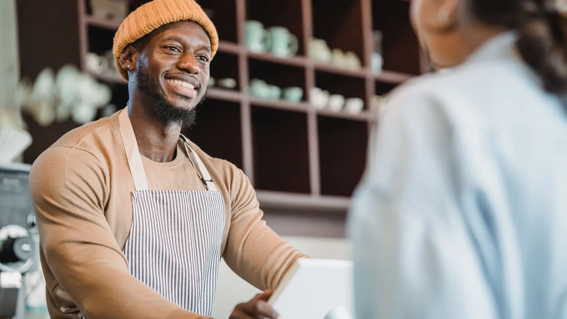 Smiling barista taking an order from a customer at a cafe counter