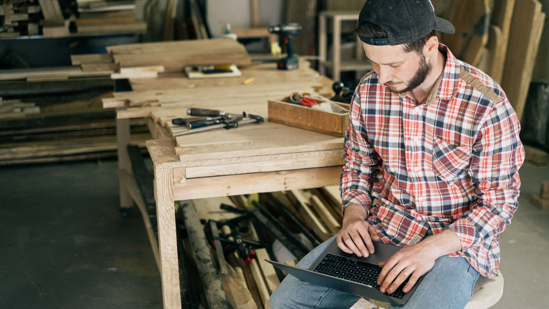 Small business owner working on a laptop in his wood workshop