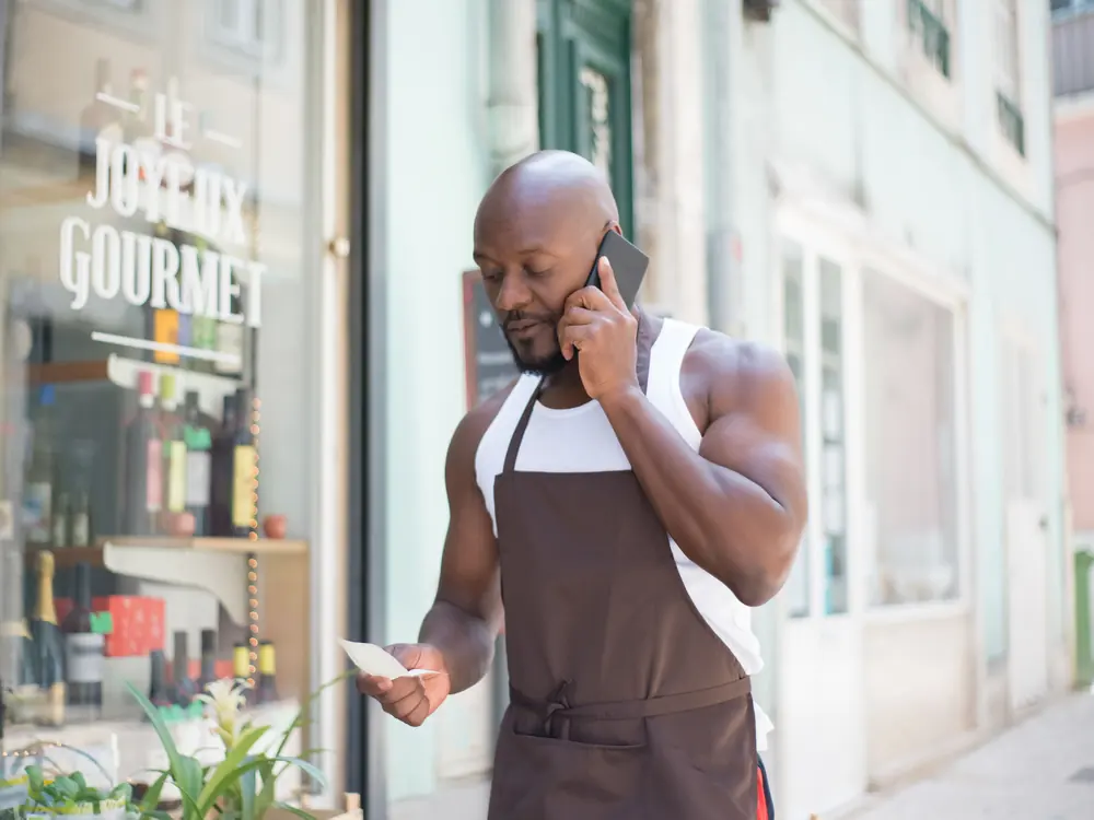 Shop owner taking a customer call outside his store